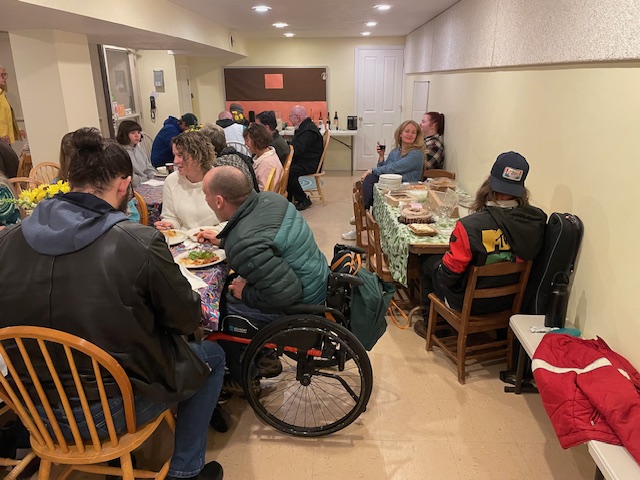 A community meal at long tables in the basement